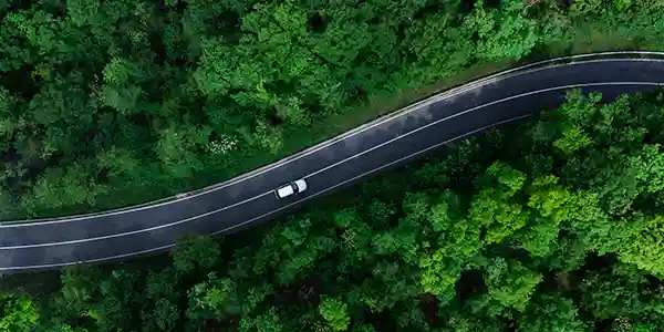 A high arial view of a vehicle travelling along a winding wilderness road.